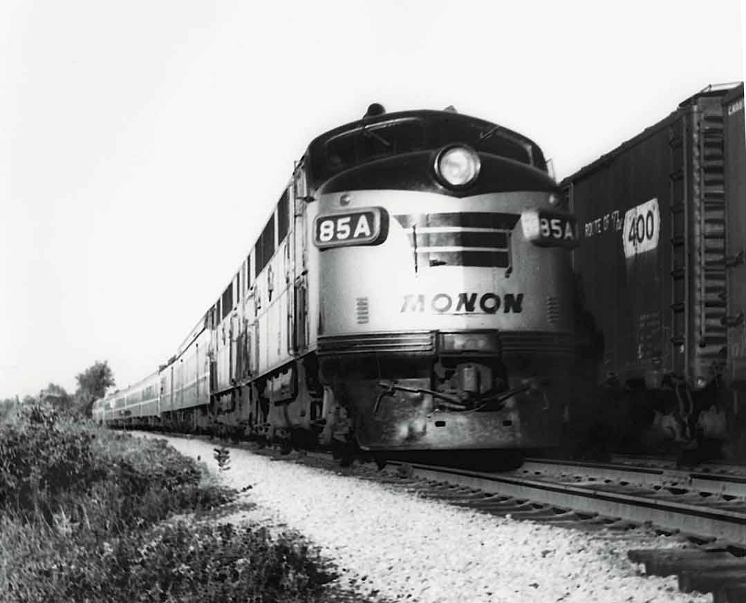 a diesel pulling passenger cars past a freight train