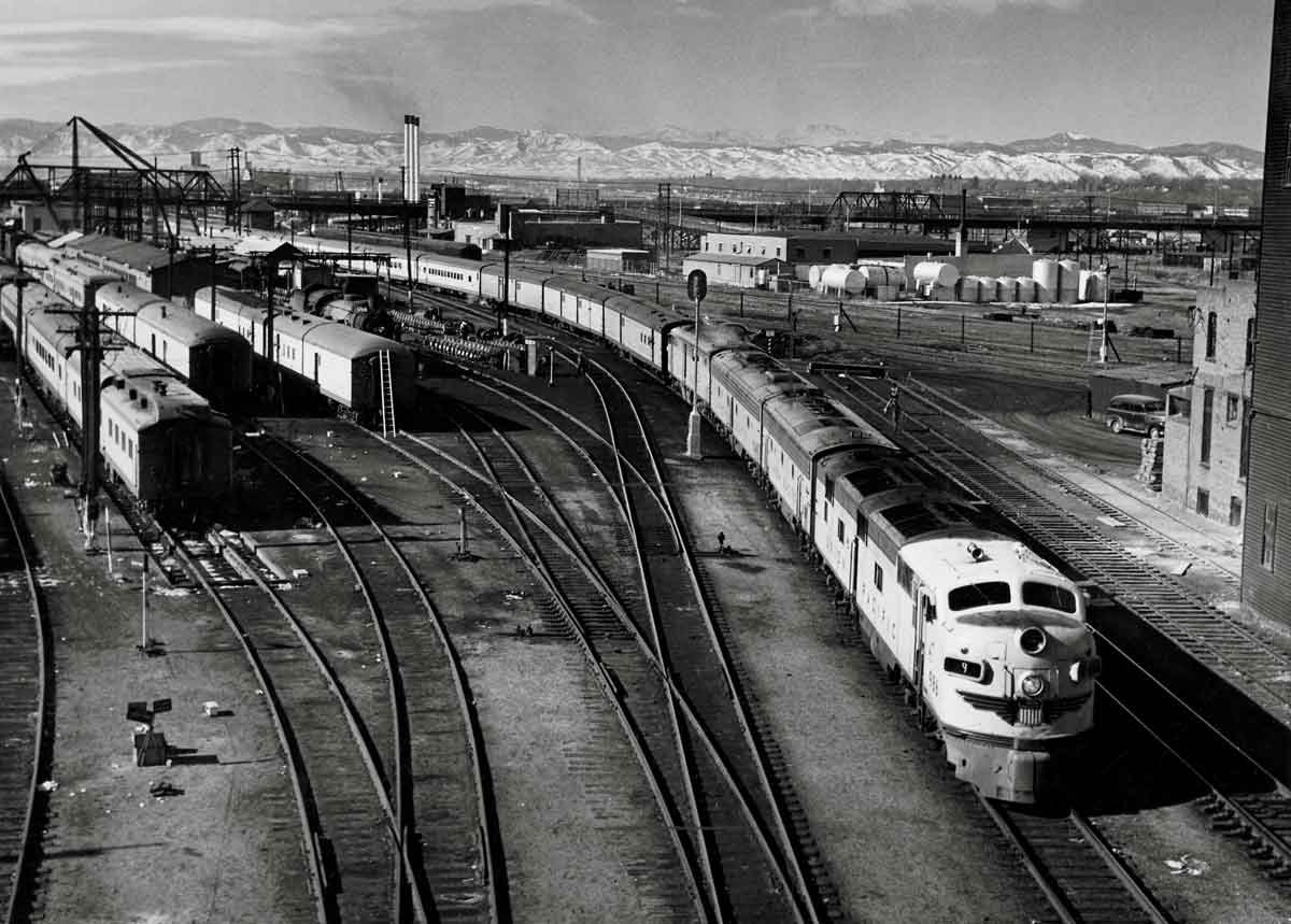 Four diesel locomotives lead passenger train out of station