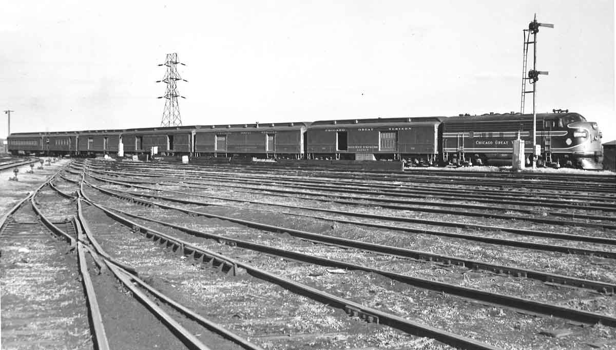 A black and white distant shot of a train arriving at a terminal