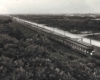 looking down on a passenger train passing by a hill