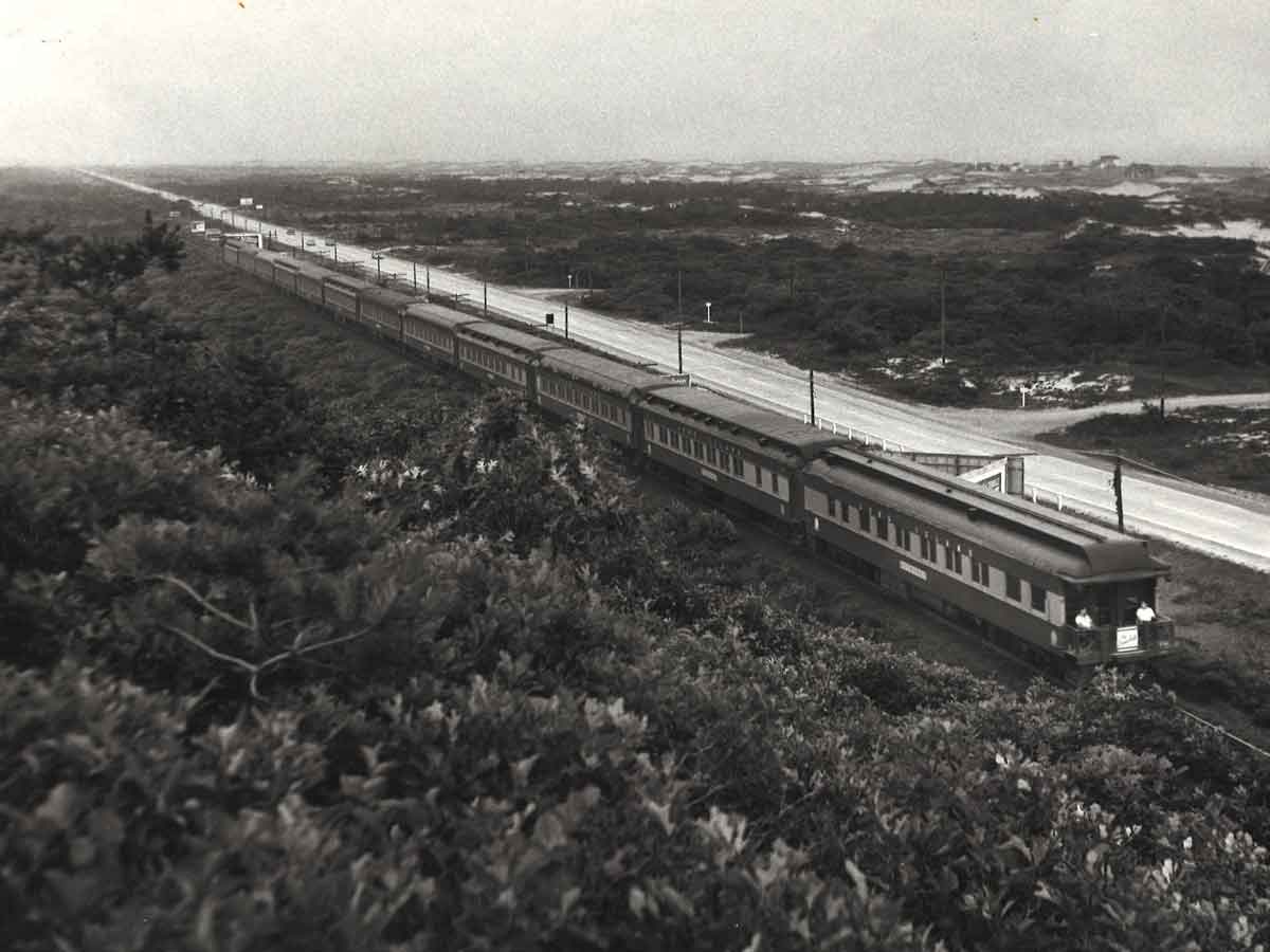 looking down on a passenger train passing by a hill
