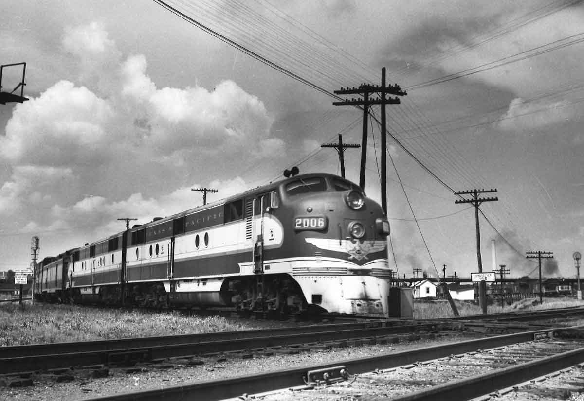 A black and white photo of an E7 locomotive stopped at an intersection on the tracks