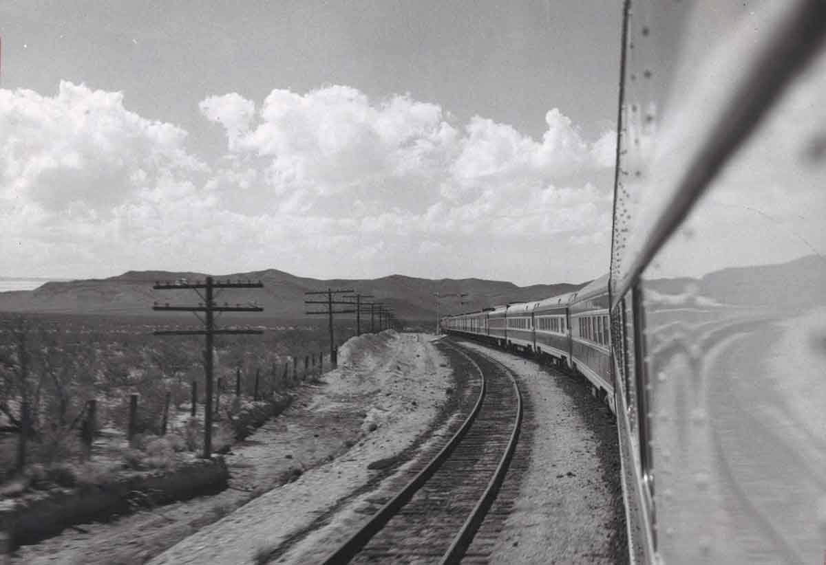 A black and white photo taken out of a window of the Texarkana–El Paso Westerner locomotive looking back at the train
