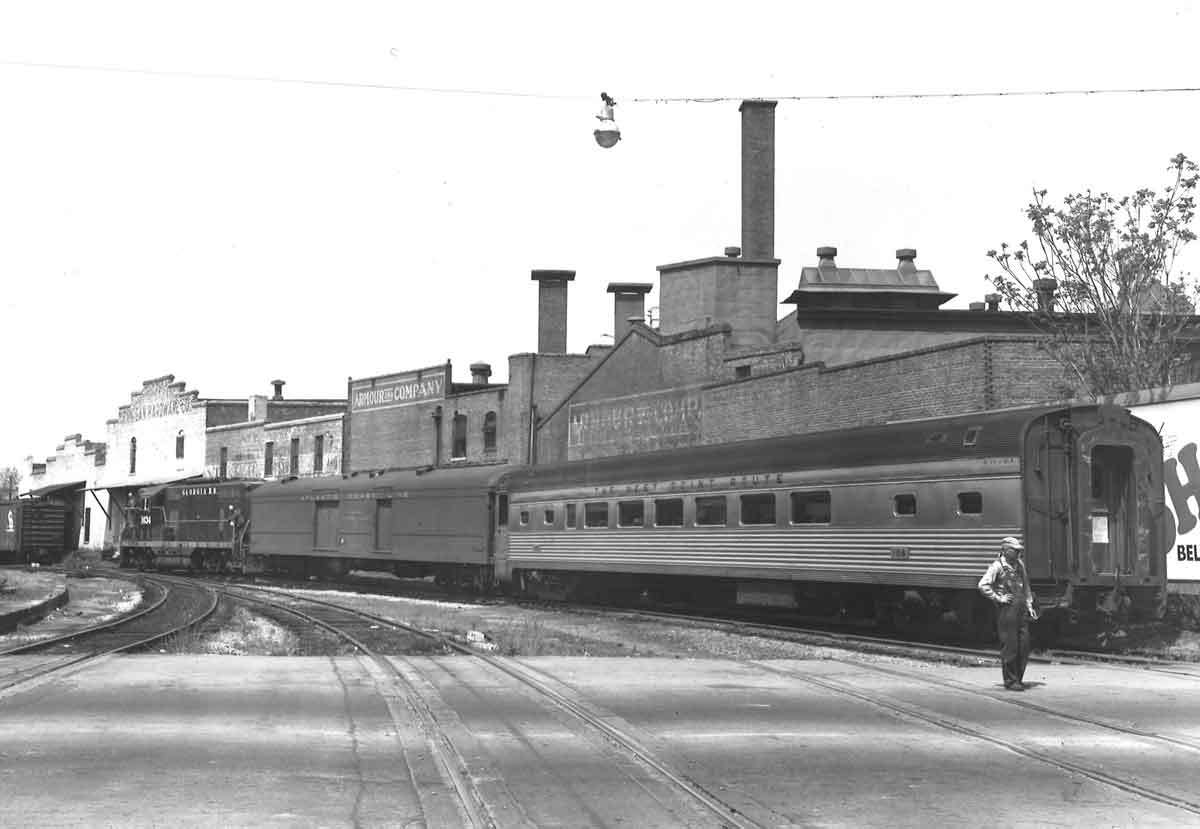 a diesel passenger train by some buildings