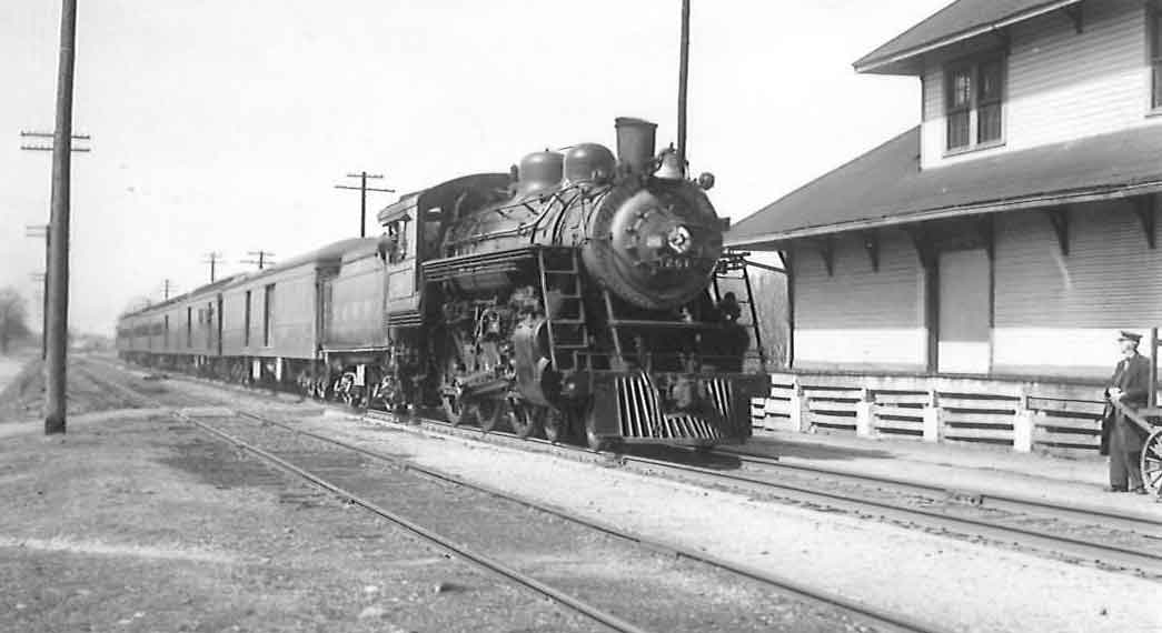 a stream engine passenger train by a building