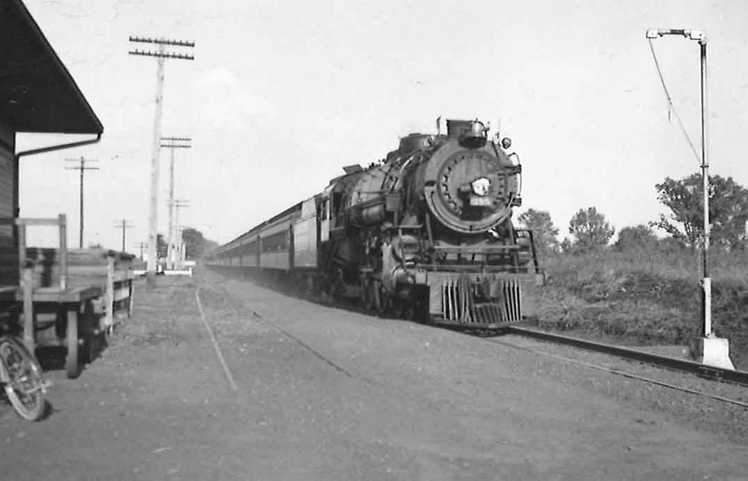 a steam engine passenger train pulling into a station
