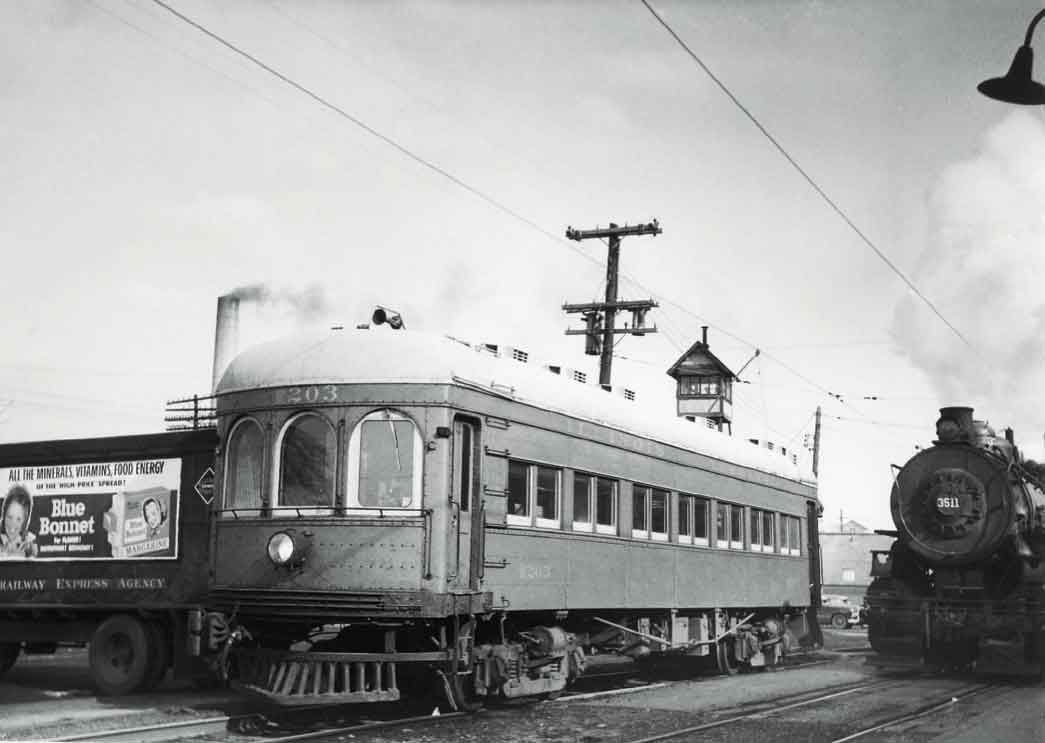 A passenger car next to a steam locomotive