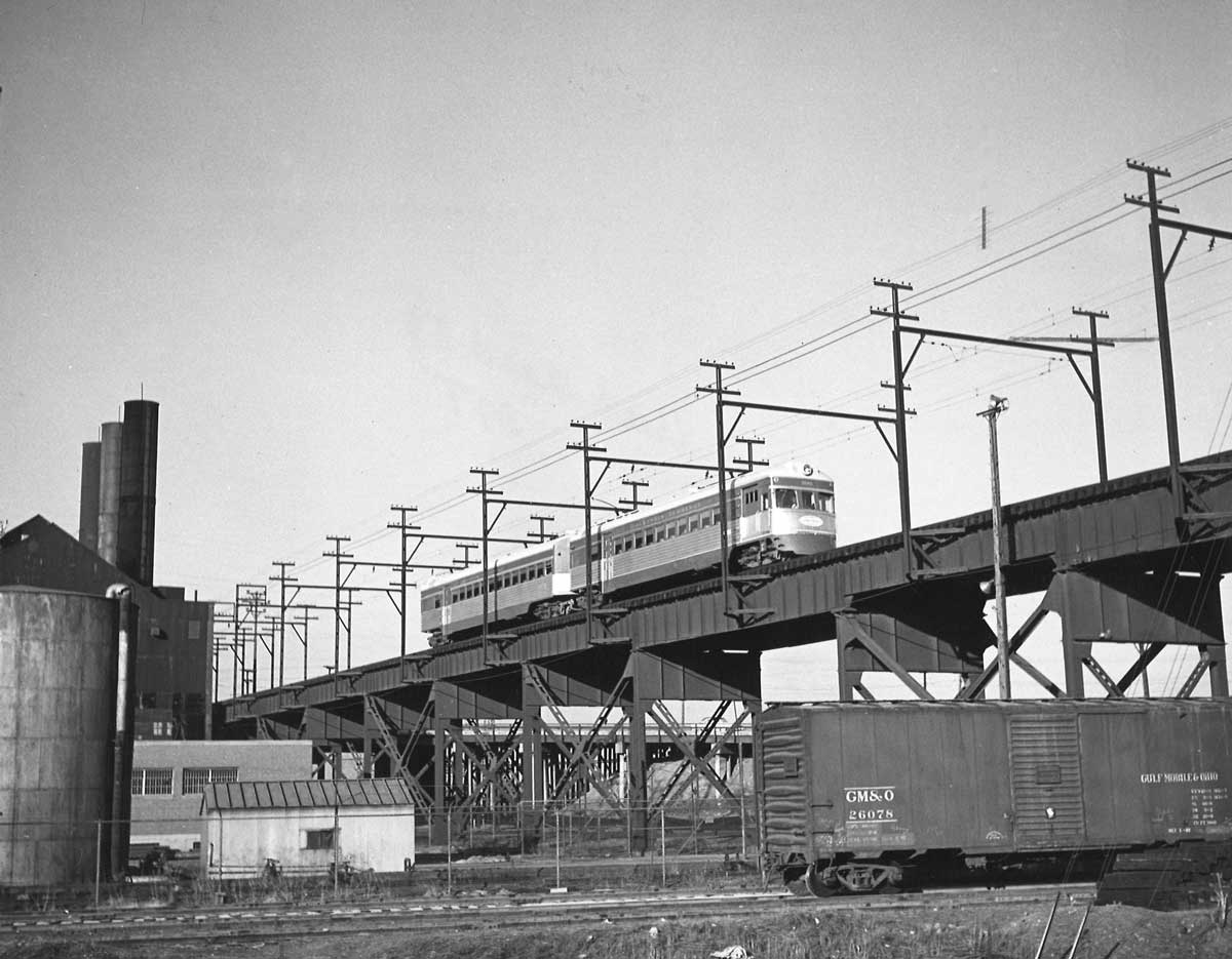 A black and white photo of a passenger car on a bridge