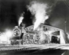Steam locomotive by train shed at night