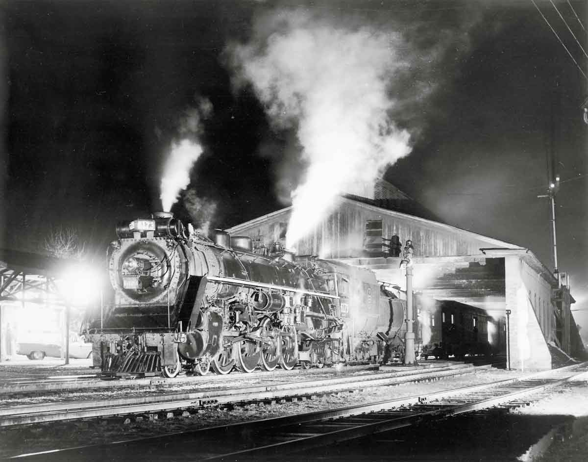 Steam locomotive by train shed at night