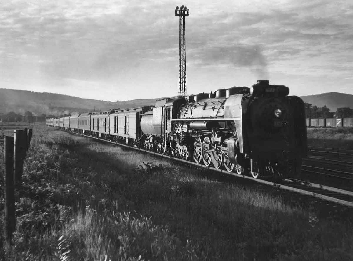 Steam locomotive with passenger train in yard