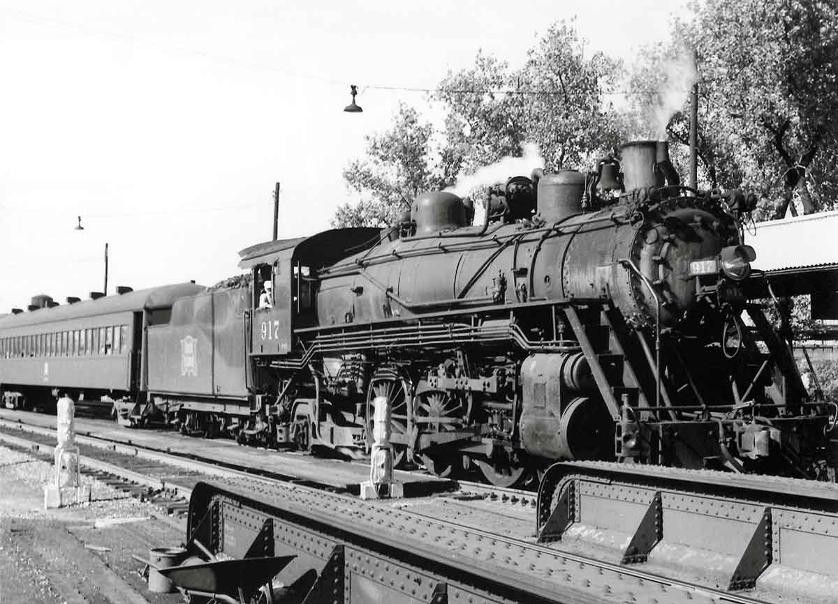 A black and white photo of a train parked at a station