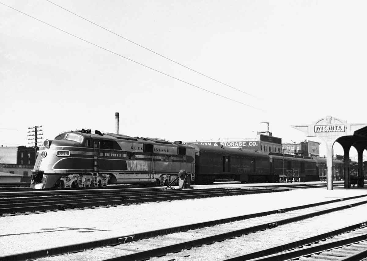 A black and white photo of a train passing a Wichita sign