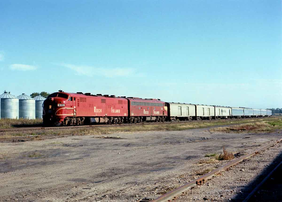 A red train passing through a rural area