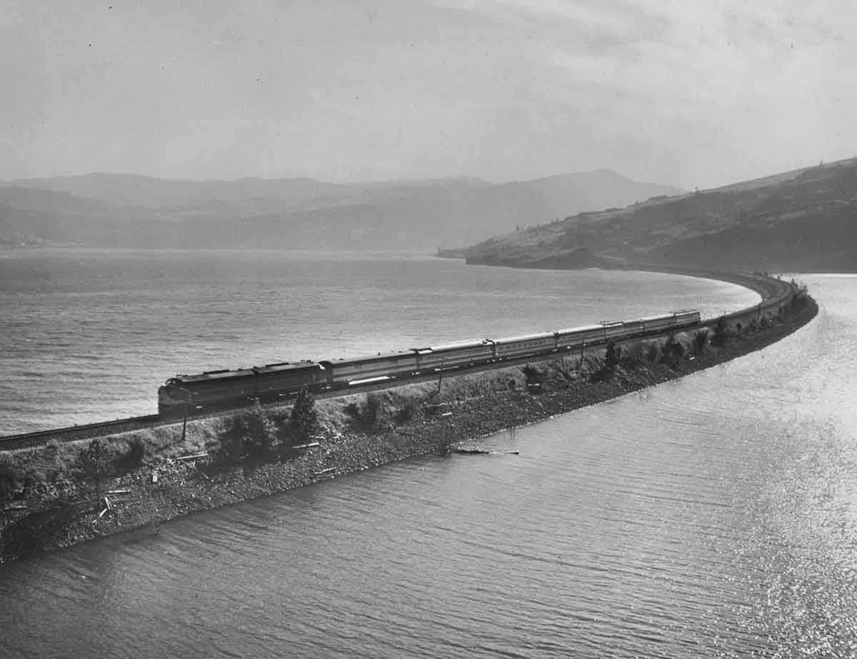 A passenger train on a narrow track surrounded by water