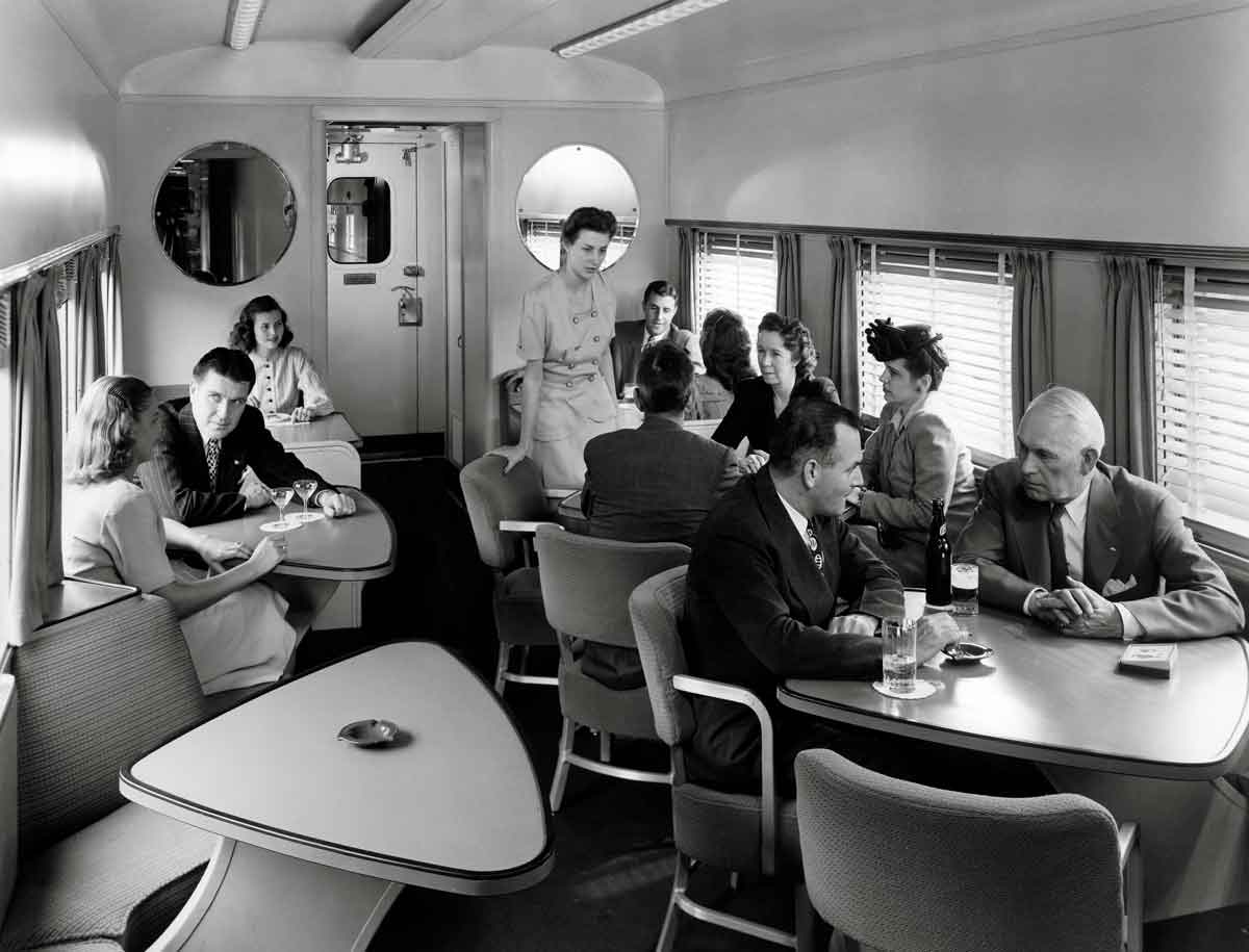 People sitting at tables, inside a train, talking