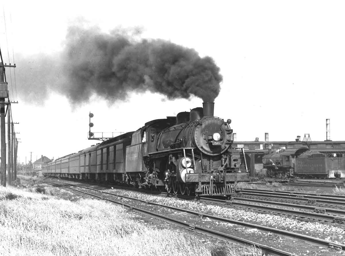 A train coming down the tracks with black smoke coming out of it