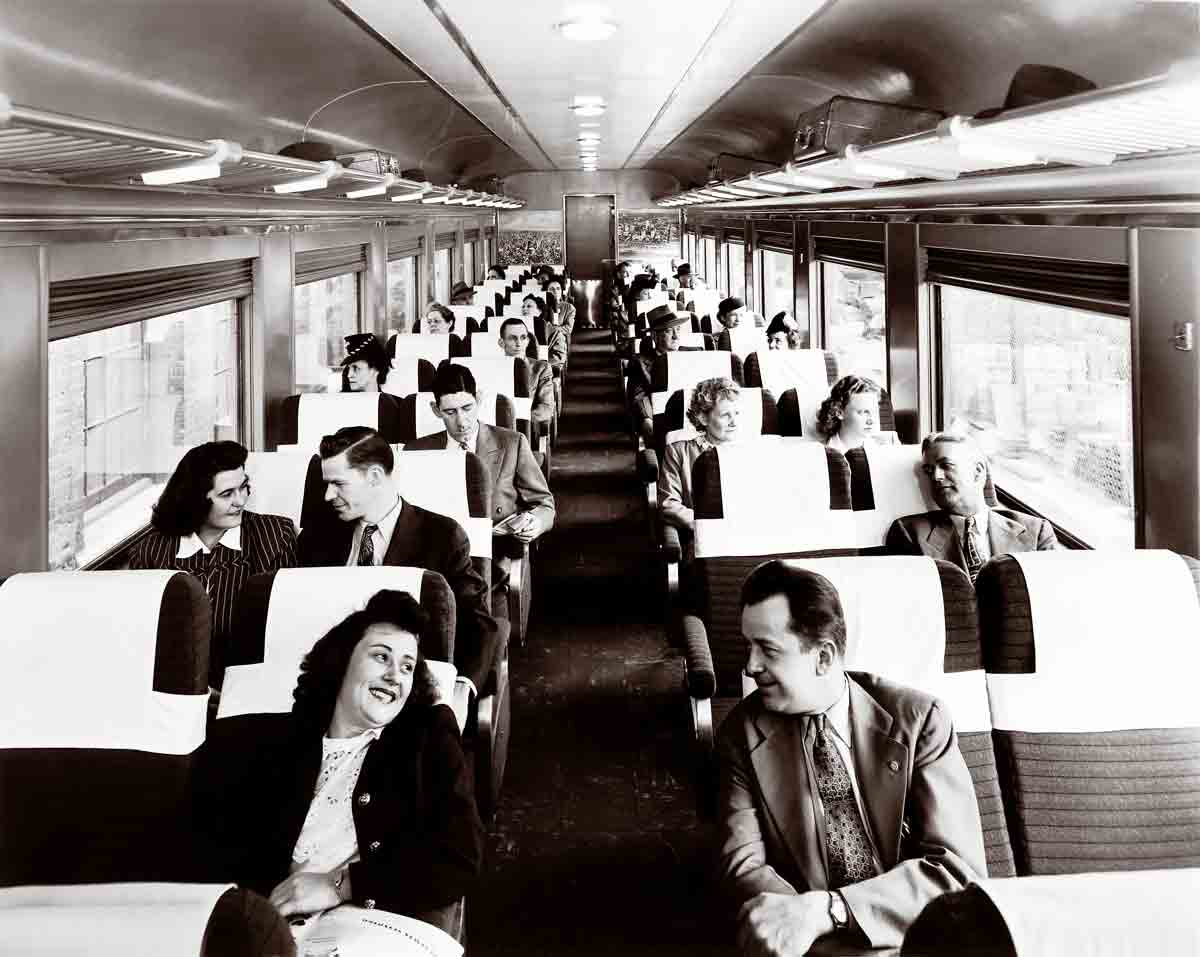 A black and white photo of passengers sitting in a train