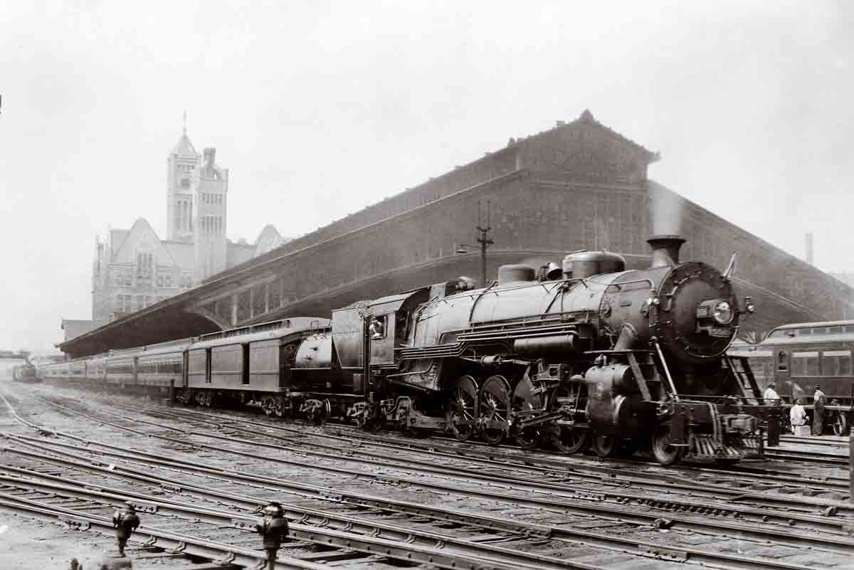 A black and white photo of a train leaving a station