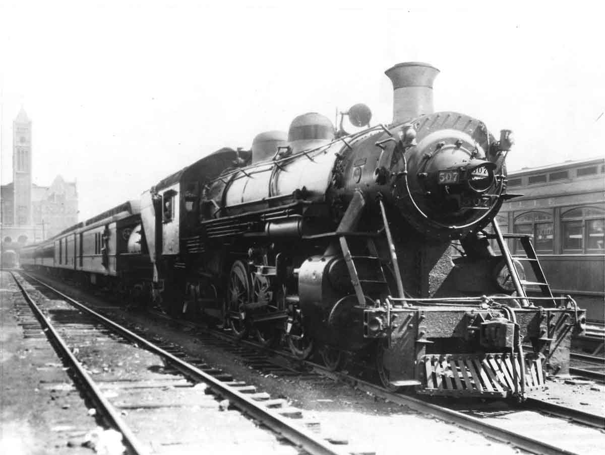 A black and white photo of a train leaving a station