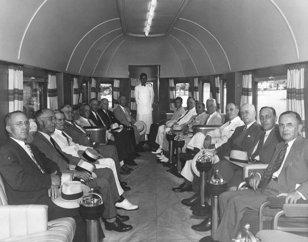 Men in suites sit in observation car