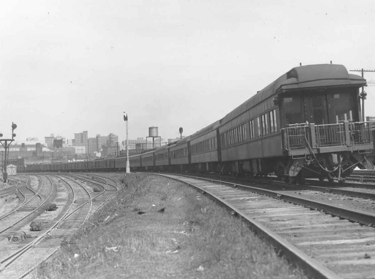 Rear of passenger train on curve by yard with signals