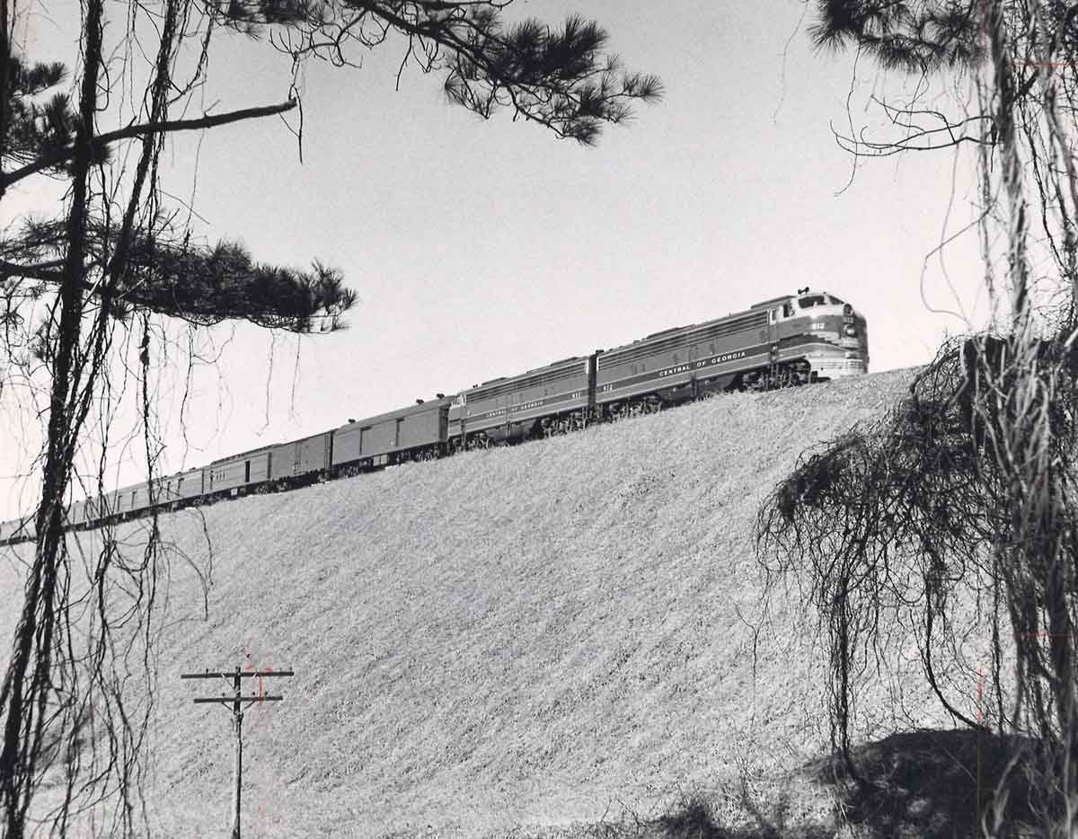 Two diesel locomotives with passenger train on high fill