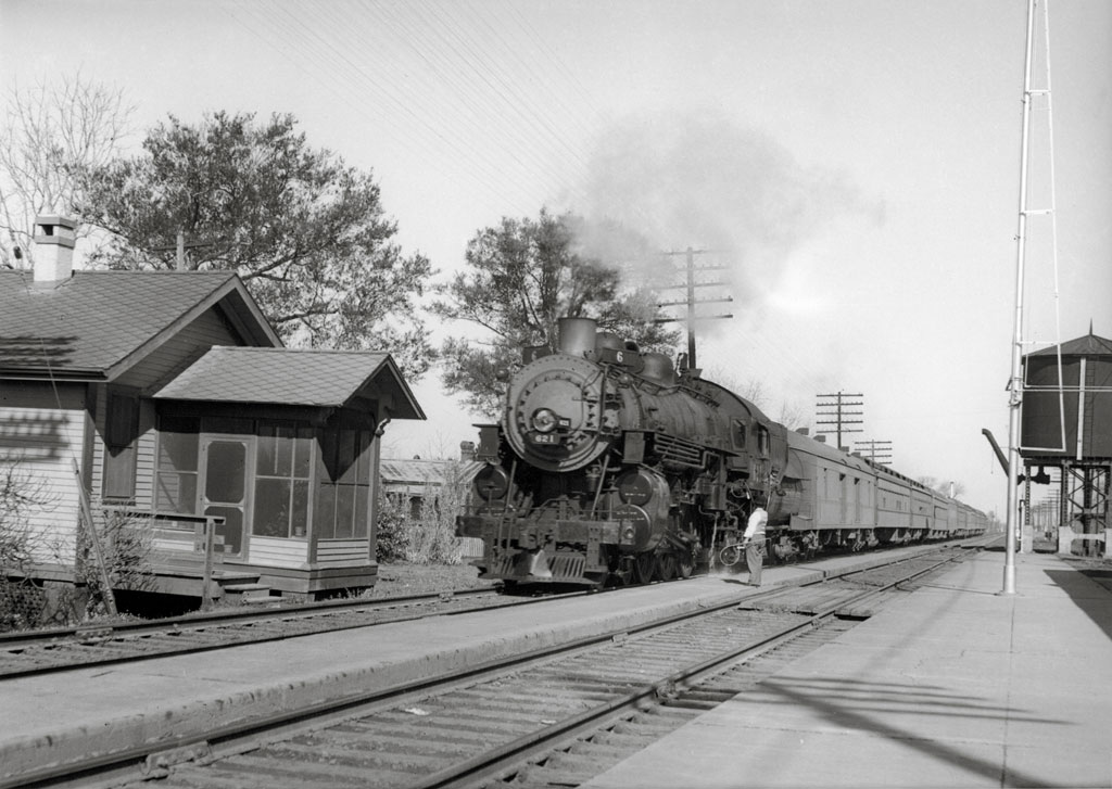A train pulling into a train station as a man watches
