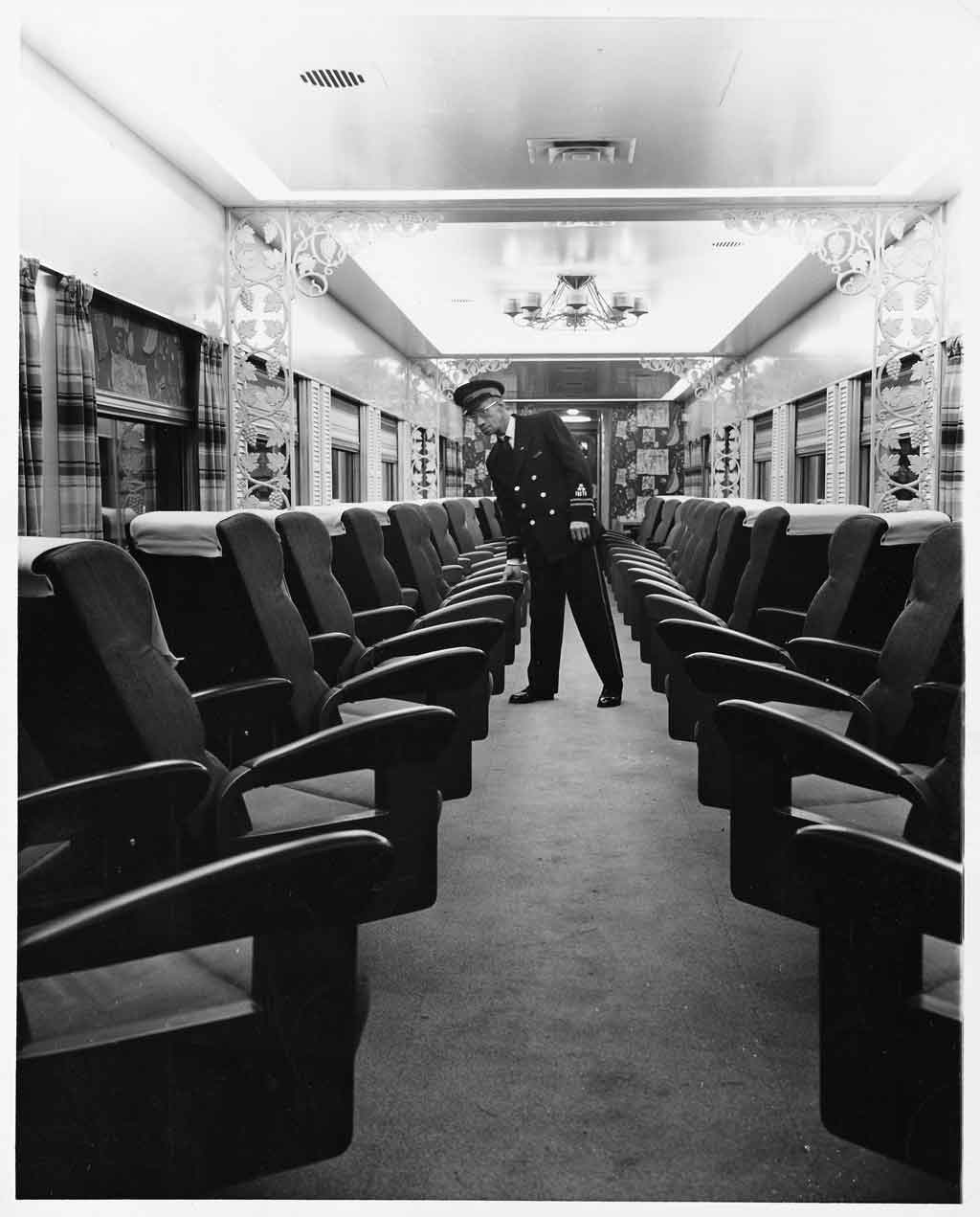 a conducter looking down the aisle on a passenger train