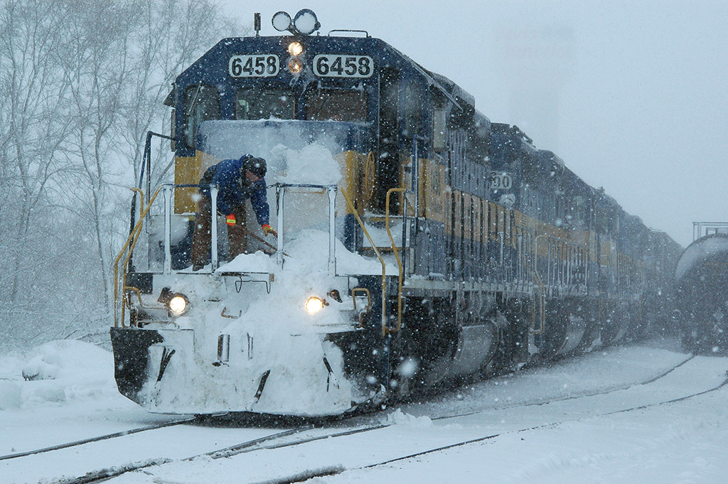 A worker cleaning snow off a train