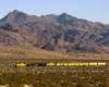 A distant shot of Big Boy passing by with mountains in the background