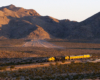 A distant shot of a train passing by with mountains in the background
