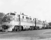Baggage is loaded while a passenger train waits in a station
