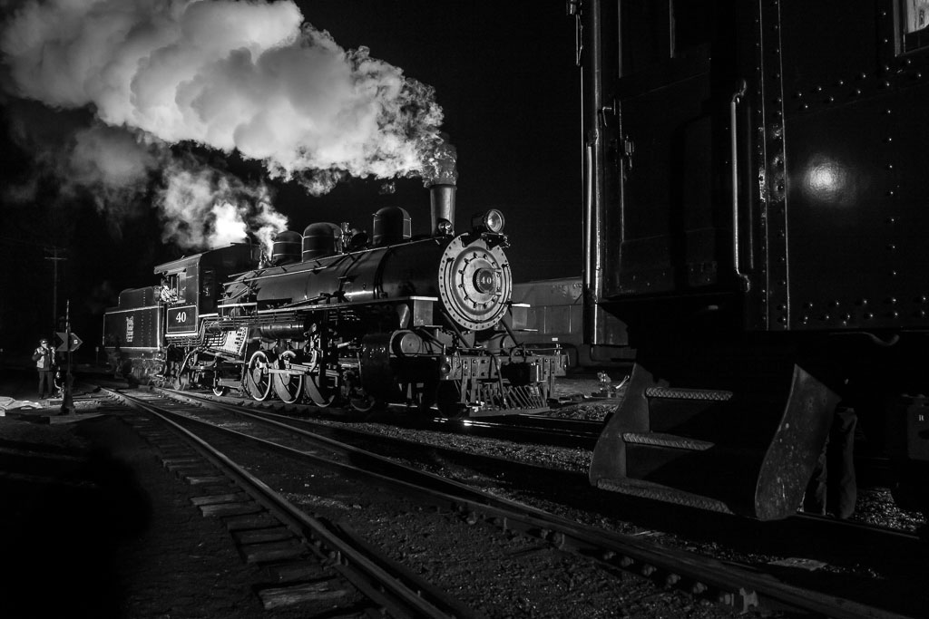 Two trains sitting on the tracks in the night