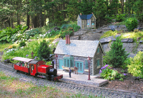 garden railway scene with structure and red and black steam engine