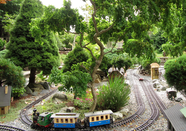 end of a garden railway with train and large tree