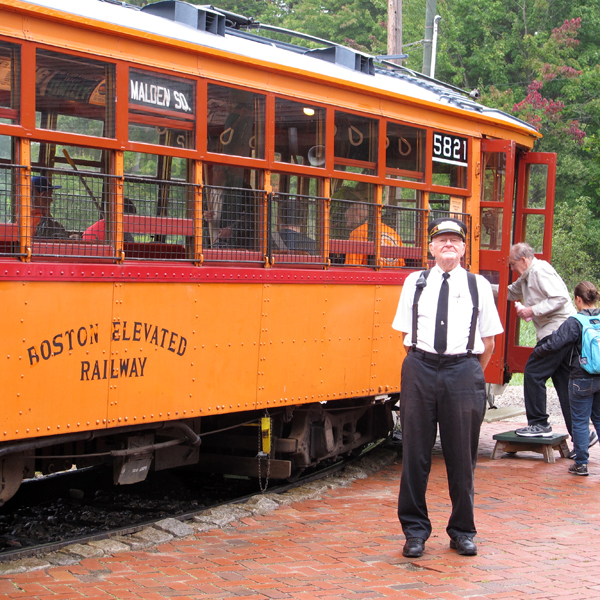 man standing next to orange trolley