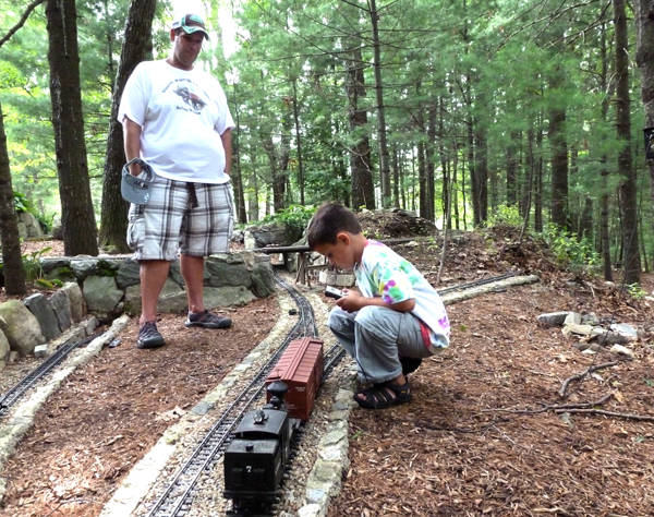 man and boy next to train on garden railway