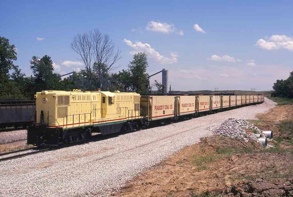 Yellow center-cab diesel with yellow coal cars