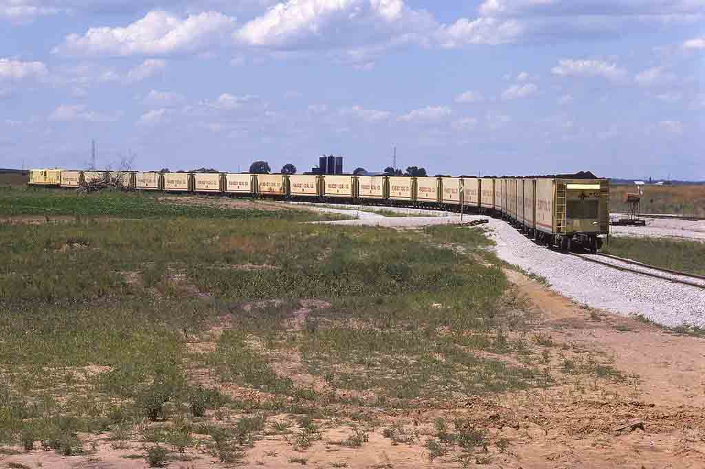 Coal train of yellow hoppers in open field