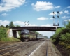 Diesel powered passenger train through signals and under a bridge