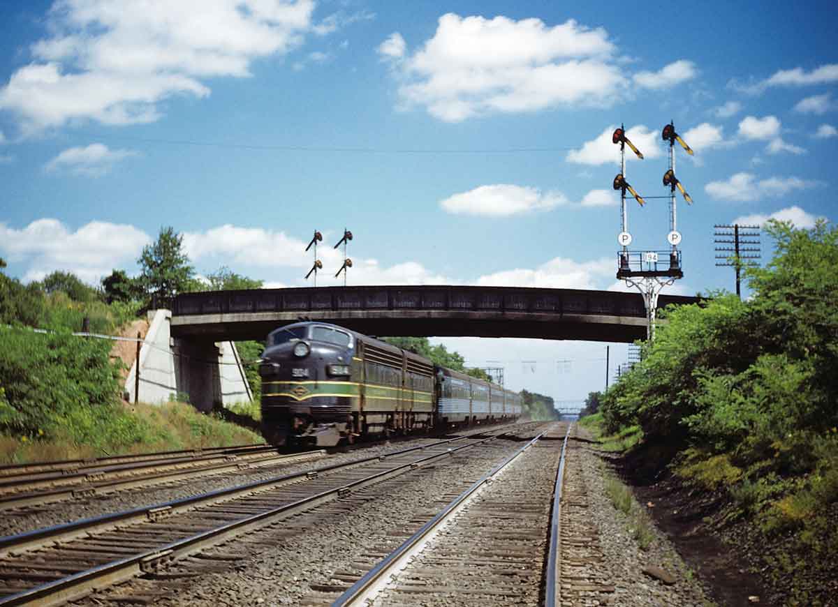 Diesel powered passenger train through signals and under a bridge