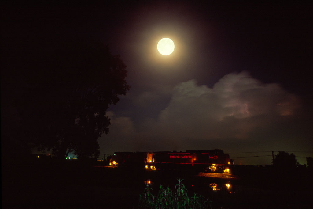 A train passing below a full moon