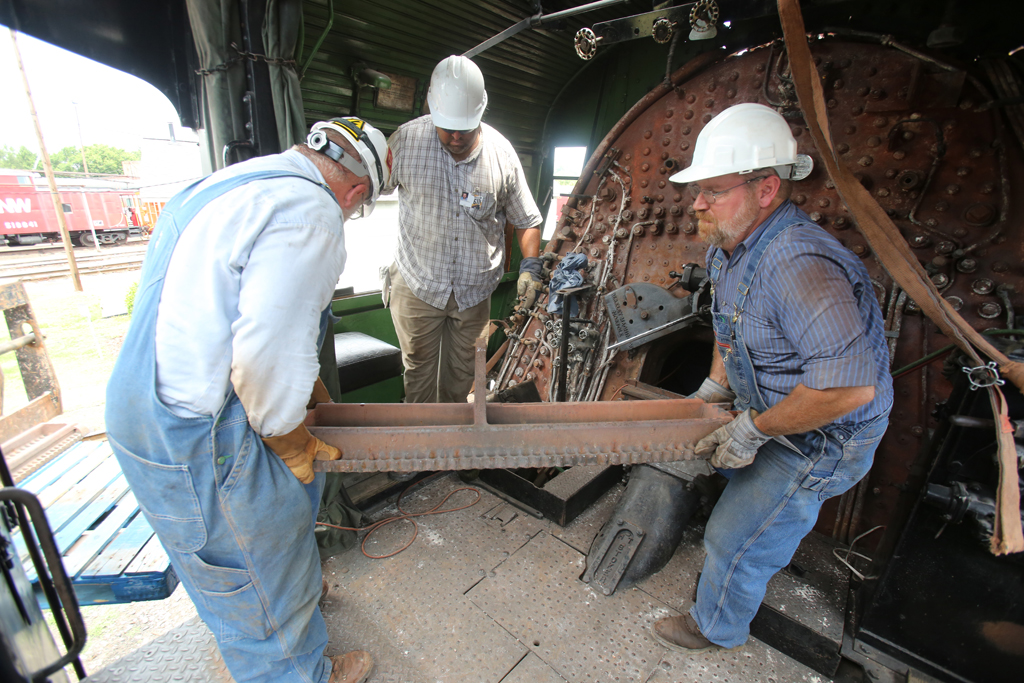 A closeup shot of three workers removing a grate from a train