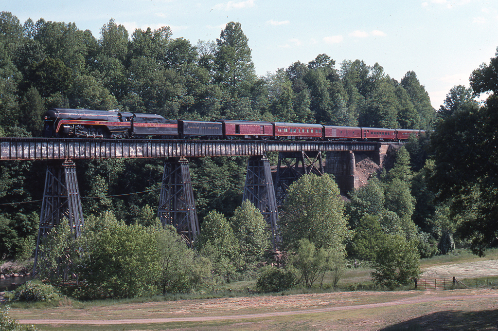 A train passing over a bridge surrounded by trees