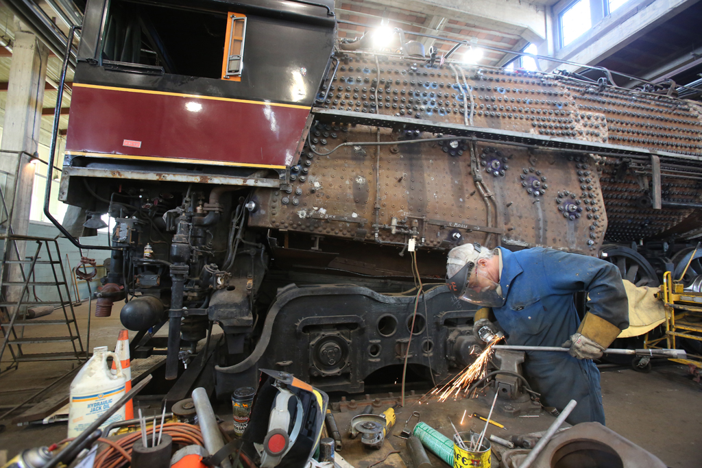 An employee working on a part of a train inside a factory