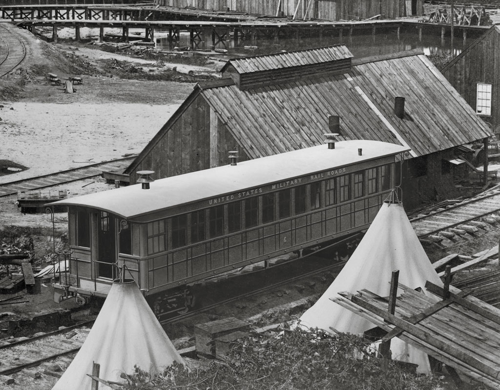 black and white train car on tracks with a building behind it