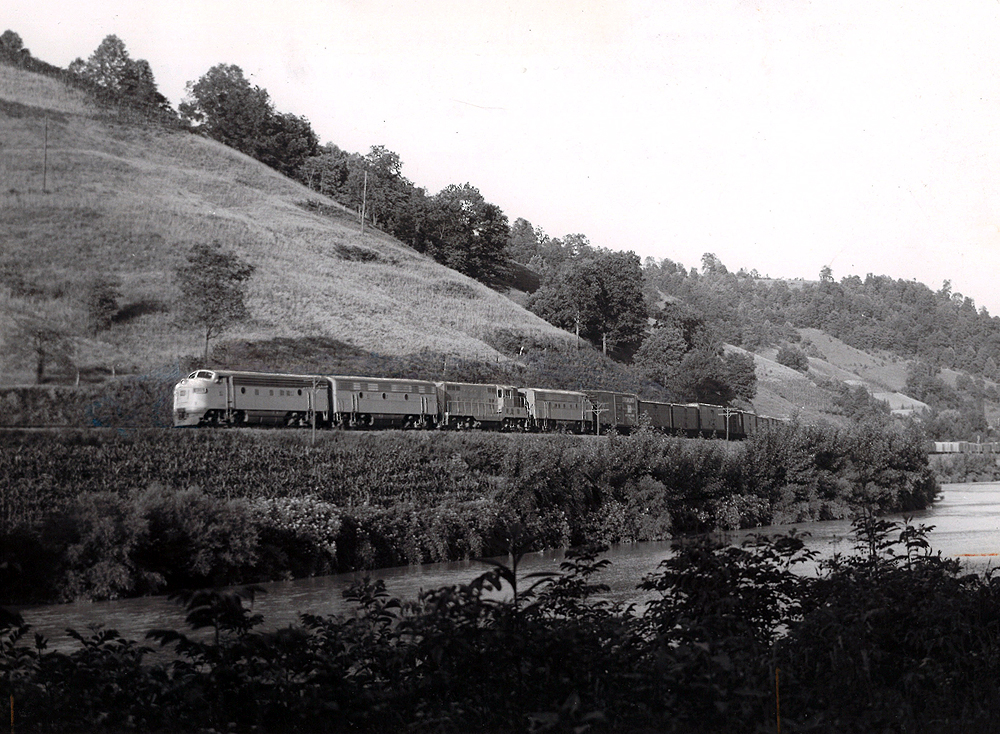 A black and white photo of locomotive No. 97 moving on the tracks past some water