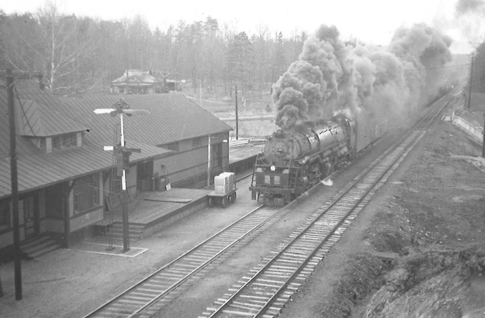 A black and white photo of 4-6-6-4 Challenger 652 moving pass a station with smoke coming out of its chimney