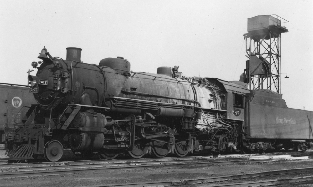 A black and white photo of a 2-8-2 steam locomotive on the tracks